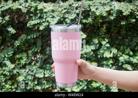 Hand on thermos tumbler mug with metal drinking straw, stock photo Stock Photo