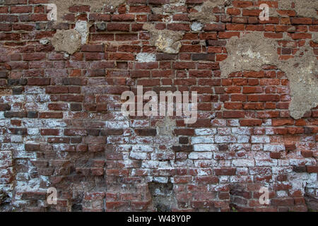 wall of old red brick with remnants of fallen plaster Stock Photo