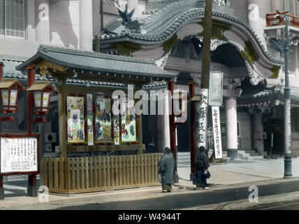 [ 1920s Japan - Tokyo Kabuki Theater ] —   Two women look at posters at Kabukiza, a theater for kabuki performances, in Ginza, Tokyo. The original Kabukiza was established in 1889 (Meiji 22). It was replaced with the building on this image in 1911 (Meiji 44). This structure was destroyed by fire in 1921 (Taisho 10), after which a new building was built in baroque Japanese revivalist style. This was demolished in 2010 (Heisei 22) to make way for a larger modern structure. The theater has been run by the Shochiku Corporation (松竹株式会社) since 1914 (Taisho 3).  20th century vintage glass slide. Stock Photo