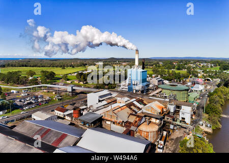 Tall chimney with evaporating white steam off Broadwater Sugar mill in tropical australia on shores of Richmond river processing sugar cane to sweet f Stock Photo