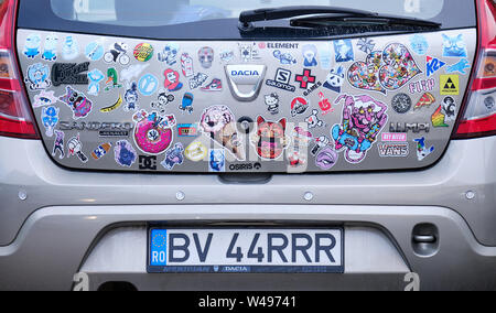 Back of hatchback Dacia car, covered in various colourful stickers, with Romanian license plate (altered number) Stock Photo