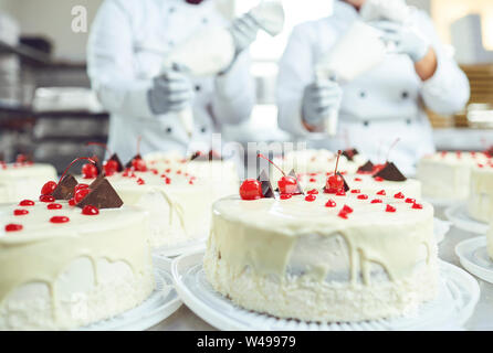 Red cherry on white cake on a table with cakes Stock Photo