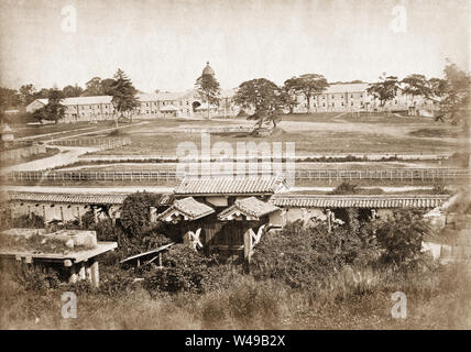 [ 1870s Japan - Imperial Guard Barracks in Tokyo ] —   Takebashi Barracks (竹橋陣営兵舎) housing the artillery battalion  of the Imperial Guard (近衛砲兵大隊) in Tokyo, in front of the Imperial Palace. The barracks were designed in 1872 (Meiji 5) by the British architect and engineer Thomas J. Waters (1843-1892). On August 23, 1878 (Meiji 11), 260 Imperial Guard members based here mutinied. The government managed to put down the mutiny and moved the Imperial Guards to a new location in what is now Minato-ku, farther removed from the Imperial Palace.  Published in The Far East Vol 6, No 12 of June 30, 1875 Stock Photo