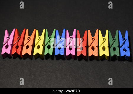 Multicolored wooden photo clips on black background. Stock Photo