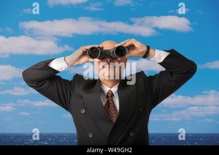 Businessman standing on a beach looking through binoculars Stock Photo