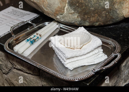 Tray containing Paschal Candles, towels, and shell are arranged neatly and ready for the Baptism ceremony at the altar. Stock Photo