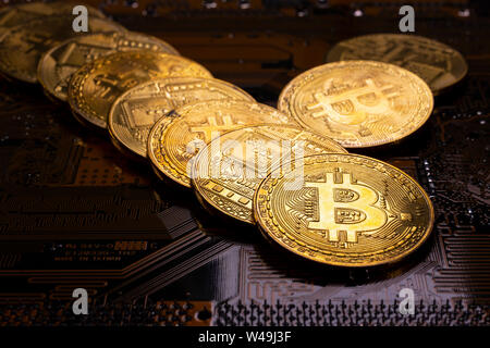 Virtual cryptocurrency money Bitcoin golden coins on a computer printed circuit board PCB. The future of money. Computational equipment. Dark image. Stock Photo