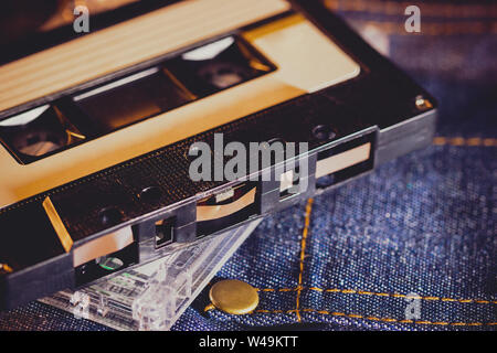 Cassette tape on jeans fabric in darkness. Concept of vintage 90s music player. Stock Photo