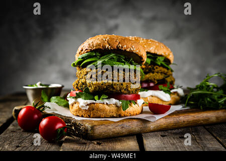 Vegan zucchini burger and ingredients on rustic wood background Stock Photo