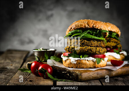 Vegan zucchini burger and ingredients on rustic wood background Stock Photo