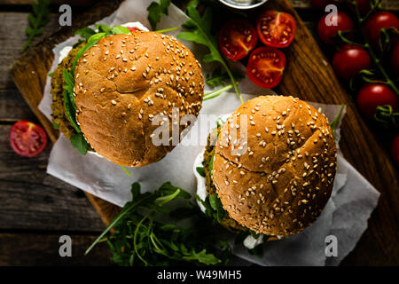 Vegan zucchini burger and ingredients on rustic wood background Stock Photo