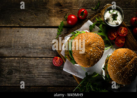 Vegan zucchini burger and ingredients on rustic wood background Stock Photo