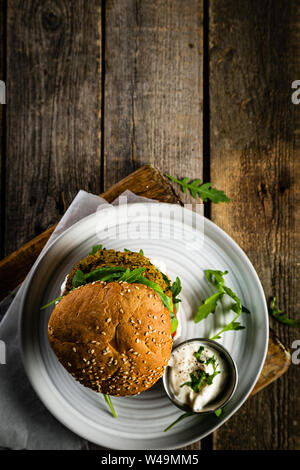 Vegan zucchini burger and ingredients on rustic wood background Stock Photo