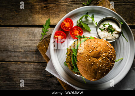 Vegan zucchini burger and ingredients on rustic wood background Stock Photo