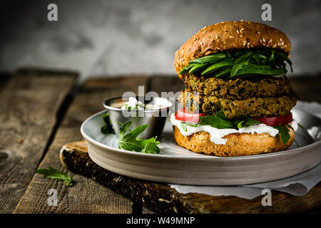 Vegan zucchini burger and ingredients on rustic wood background Stock Photo