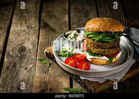 Vegan zucchini burger and ingredients on rustic wood background Stock Photo