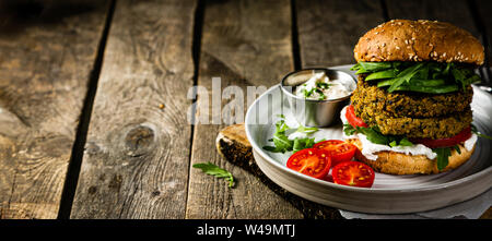 Vegan zucchini burger and ingredients on rustic wood background Stock Photo