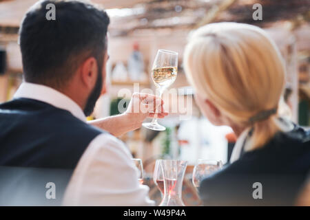 Two professional cavists studying characteristics of wine sample in flute Stock Photo