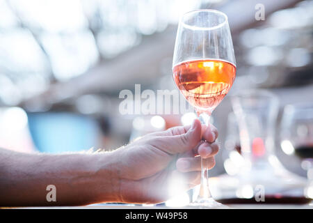 Human hand holding bokal of white wine or brandy while going to drink it Stock Photo