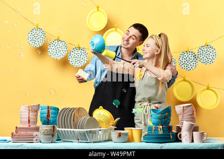attractive young couple dusting the plates . hobby , daily routine. close up photo.happy young man and woman using plate like a mirror in the kitchen Stock Photo