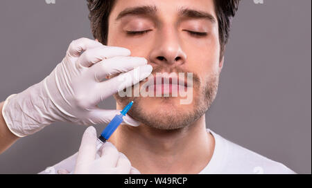 Young male patient receiving botulinum injection in lips Stock Photo