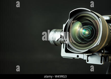 Close-up of wide angle lens in a dsl camera and gimbal stabilizer, with low-key lighting and a black background