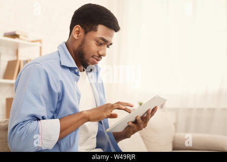 Black man using digital tablet on couch at home Stock Photo