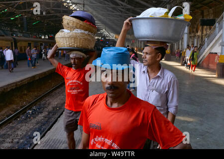 Porters at Chhatrapati Shivaji Maharaj Terminus (CSMT) in Mumbai, India, waiting for a train to deliver their goods from a nearby fish market Stock Photo