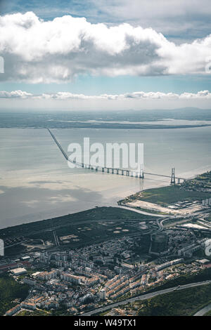 Aerial panorama view over the 25 de Abril Bridge. The bridge is connecting the city of Lisbon to the municipality of Almada on the left bank of the Stock Photo