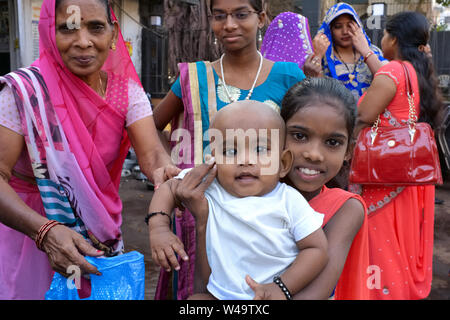 A young girl in Mumbai, India, part of a large joint family, proudly holding her baby brother into the camera Stock Photo