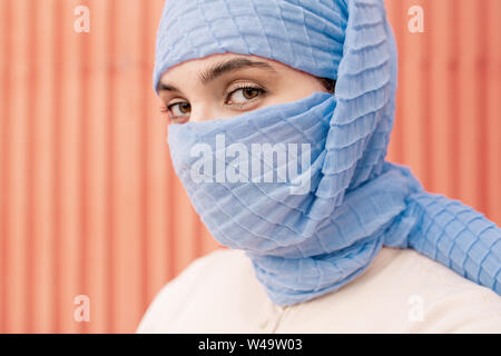 Young beautiful Arabian female with her face hidden behind blue hijab Stock Photo