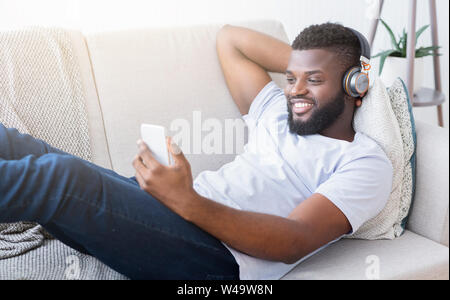 Black man in headphones watching movie on smartphone Stock Photo