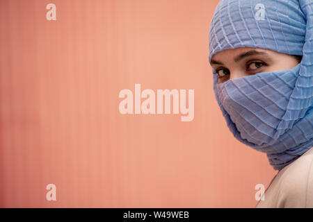Young beautiful islamic female with her face hidden behind blue hijab Stock Photo