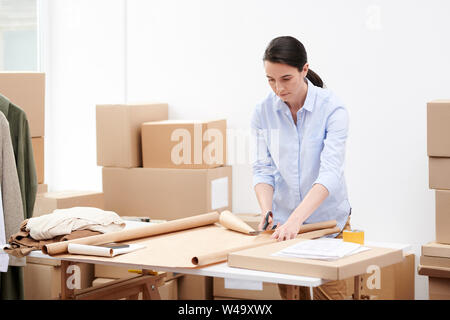 Manager of online shop office cutting wrapping paper by workplace Stock Photo