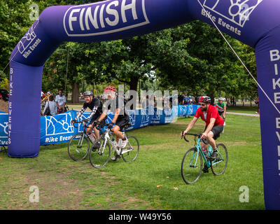 Cambridge, UK. 21, July, 2019. Three riders cross the finish line of the London to Cambridge bike ride.  The route of the ride covers around 60 miles starting in Pickett’s Lock in north London and ending at Jesus Green in the heart of Cambridge. Credit: Alex Skinner/Alamy live news Stock Photo