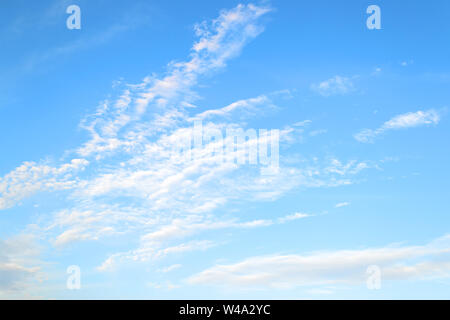 White translucent stratus and cirrus clouds high in the blue summer sky. Different cloud types and atmospheric phenomena. Skyscape on a sunny day. Stock Photo