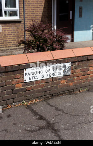 Slightly worn sign on low wall reading 'Parking of vehicles etc is forbidden' Stock Photo