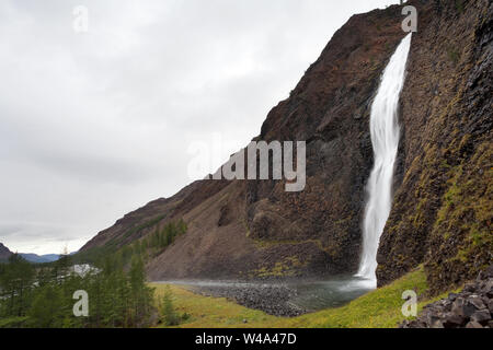 A breathtaking view of a cascading waterfall flowing into a mountain ...