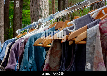 Beautiful colorful clothes on hangers in a beautiful summer day in the park Stock Photo