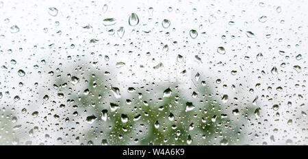 Large drops of water on the glass. Raindrops on the windshield of a car against the background of the sky sky. Stock Photo