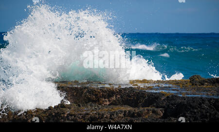 A wave crashing against a rock outcropping on Oahu Hawaii's south shore. Stock Photo
