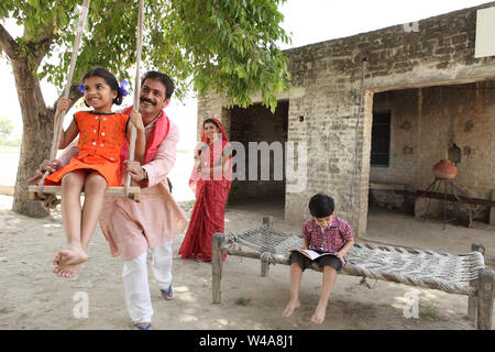 Man pushing his daughter on the swing Stock Photo