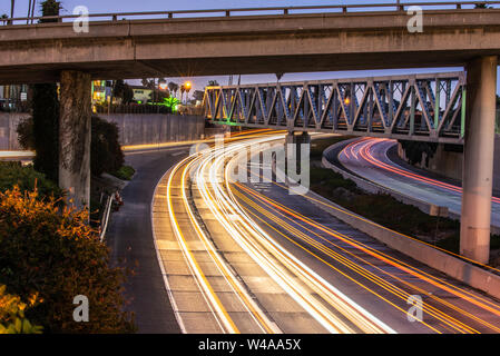 Streaking headlights and tail lights of the flowing traffic of the 101 freeway as it passes under bridges in Ventura. Stock Photo