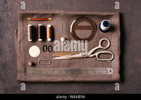 Sewing tools on the brown table and linen cloth, flat lay geometric composition Stock Photo
