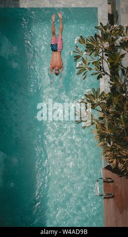 Vertical shot of a male in american flag swimsuit swimming in a pool Stock Photo