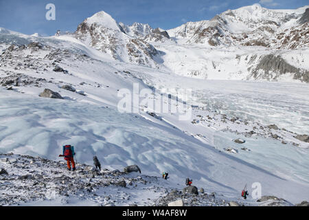 Backpacking ski tour climbers against Sophiyskiy glacier in Altay high mountains. Siberia. Russia. Stock Photo