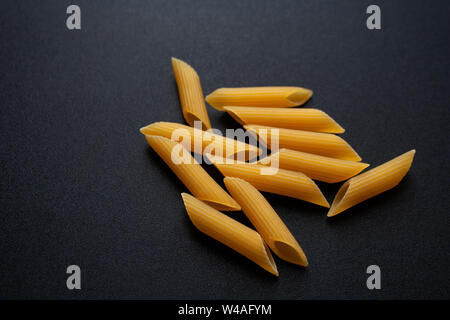 Heap of raw penne rigate pasta isolated on black background Stock Photo