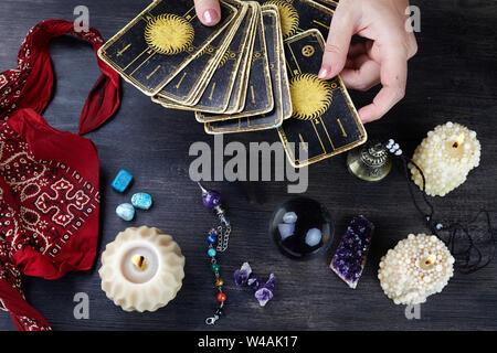 Fortune teller female hands and tarot cards on dark wooden table. Divination concept. Stock Photo