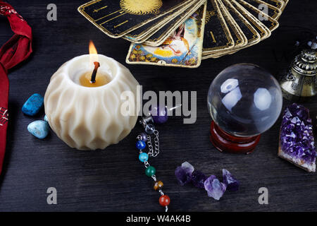 Still life with the tarot cards, magic stones and candles on wooden table. Fortune telling seance or magic ritual. Stock Photo