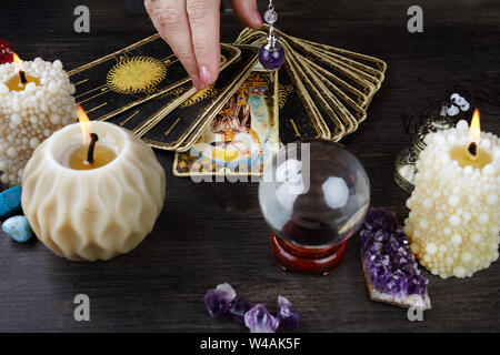 Still life with the tarot cards, magic stones and candles on wooden table. Fortune telling seance or magic ritual. Stock Photo